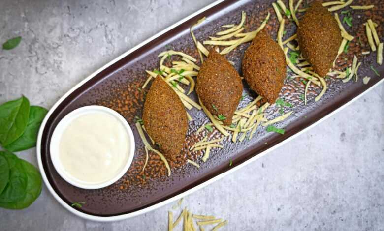 A plate with three meatballs and a dipping sauce