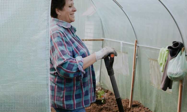 Woman Holding a Shovel Standing Inside a Foil Greenhouse