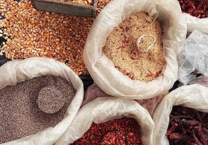 Top view of diverse spices and grains in bags at Xilitla market, México, showcasing rich textures and colors.