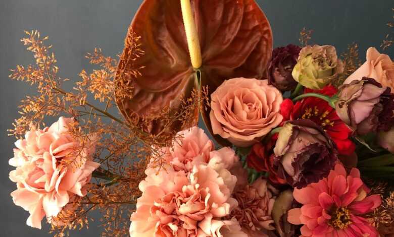 Crop person with bunch of various flowers including roses and gerberas with decorative plants branches