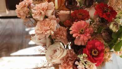 High angle of bunch of fresh red and pink flowers with ribbon placed on wooden floor under table