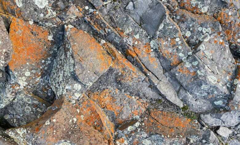 Top view of rough natural rock surface with cracks and orange rust as abstract background