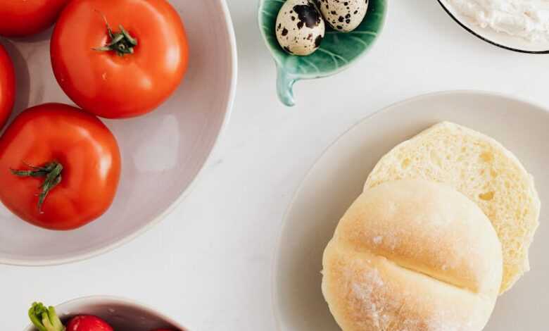 Top view of fresh vegetables and vitamin salad together with quail eggs and cottage cheese complemented with wheat bread on plates and in bowls on marble table