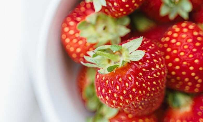 Ripe strawberries in white plate on table