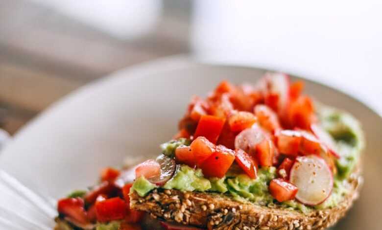 Delicious sandwiches with avocado and juicy tomato slices on rye bread pieces with sesame seeds