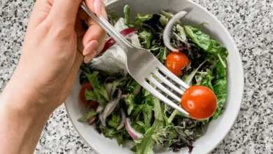 Person eating tomato from salad