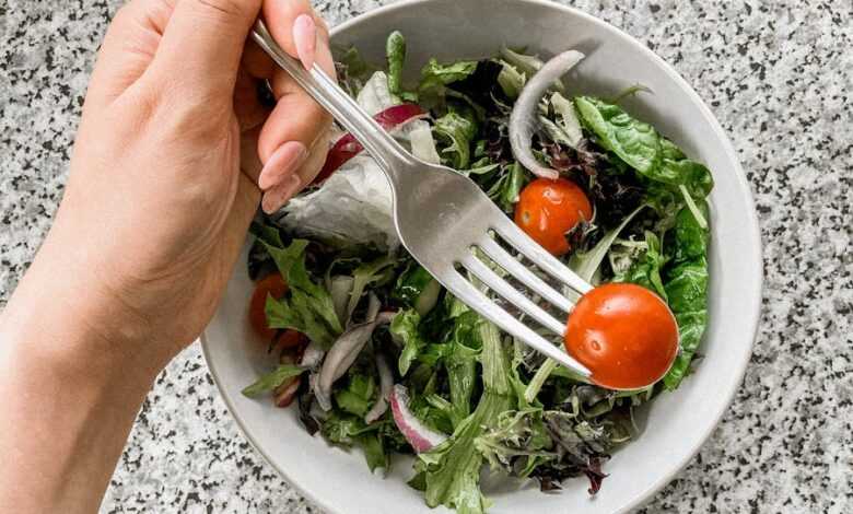 Person eating tomato from salad