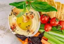 Top view of hummus with vegetables and crackers, perfect for healthy snacking.