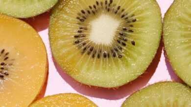 Top view of composed fresh tasty green kiwi slices placed on pink background