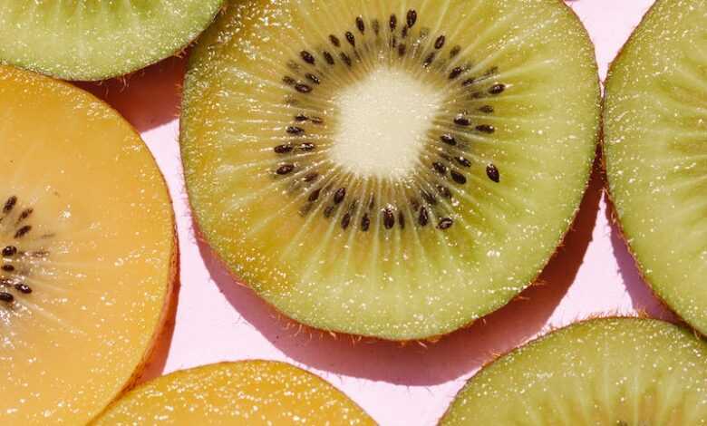 Top view of composed fresh tasty green kiwi slices placed on pink background