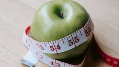 Green apple with measuring tape on table in kitchen