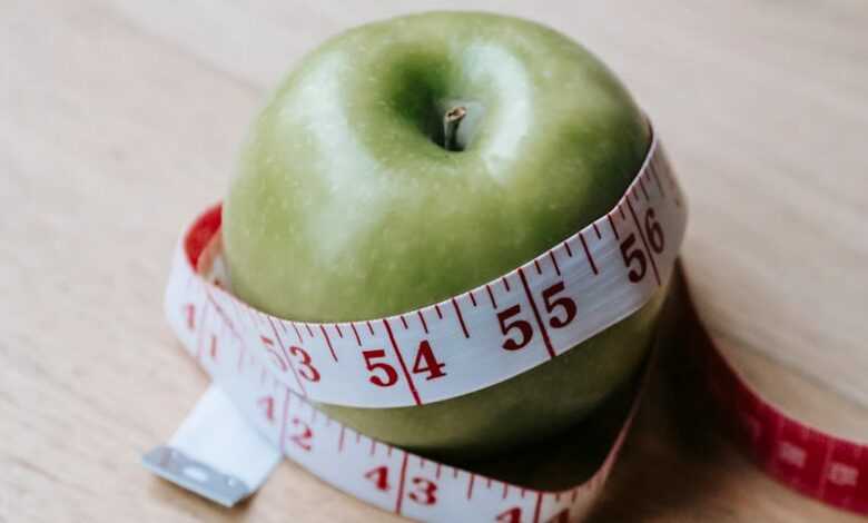 Green apple with measuring tape on table in kitchen