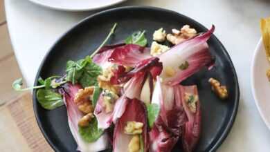 From above of healthy salad with fresh red lettuce and walnuts in plate placed on table with appetizing fish and roasted cauliflower