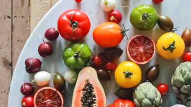 Top view of assorted exotic fruit with citrus and various vegetables of tomatoes and onions on round table