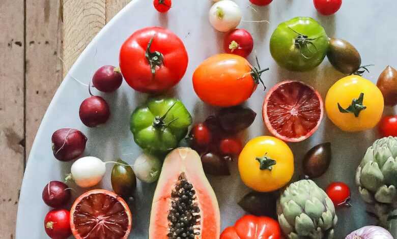 Top view of assorted exotic fruit with citrus and various vegetables of tomatoes and onions on round table