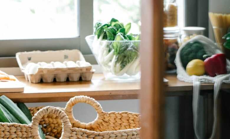 Wicker basket placed on stool near counter with eggs and vegetables in light kitchen