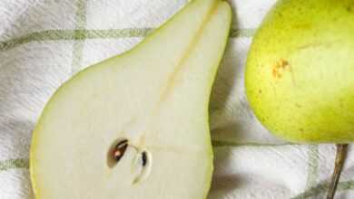 From above of fresh ripe pieces of green pears placed on white fabric on table in light place