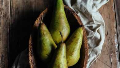 Bowl with ripe green pears and cotton napkin placed on lumber rustic table