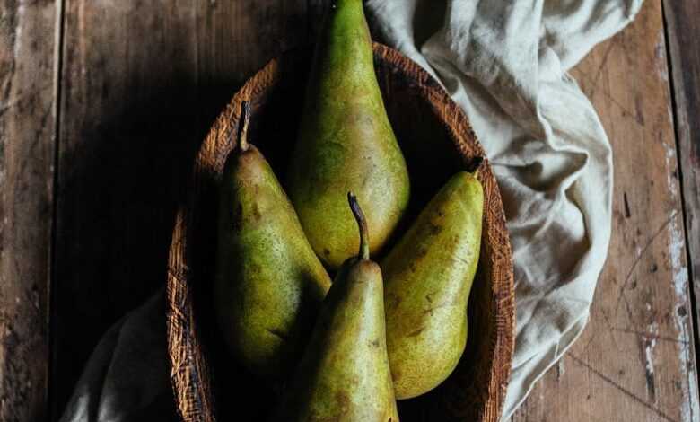 Bowl with ripe green pears and cotton napkin placed on lumber rustic table