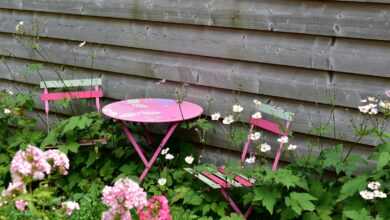 a pink table and two pink chairs in a garden