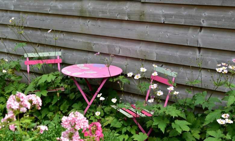 a pink table and two pink chairs in a garden