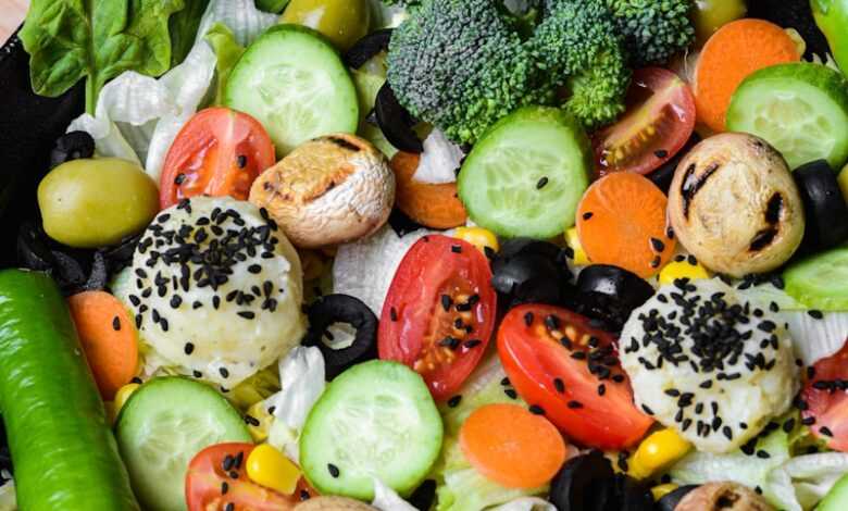 a black bowl filled with vegetables on top of a wooden table