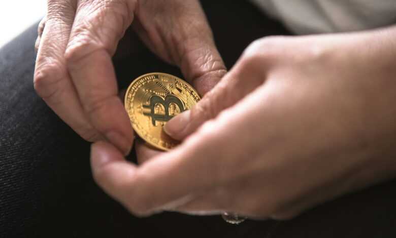 person holding round gold-colored Bitcoin