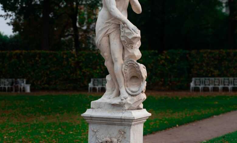 a statue of a woman holding a bird in a park