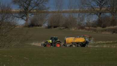 a tractor pulling a trailer behind it through a field