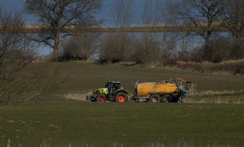 a tractor pulling a trailer behind it through a field