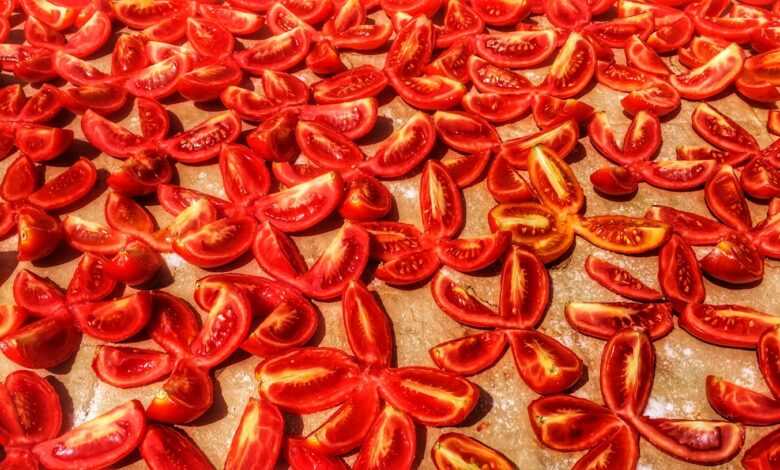 a table topped with sliced tomatoes on top of a wooden cutting board