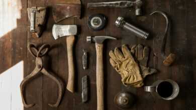 clothes iron, hammer, axe, flashlight and pitcher on brown wooden table