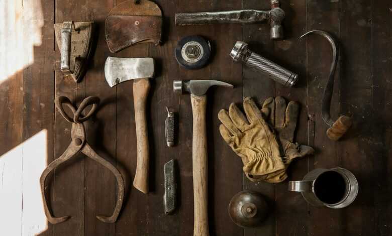 clothes iron, hammer, axe, flashlight and pitcher on brown wooden table