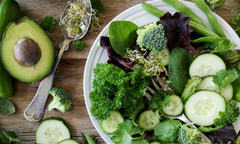 sliced broccoli and cucumber on plate with gray stainless steel fork near green bell pepper, snowpea, and avocado fruit