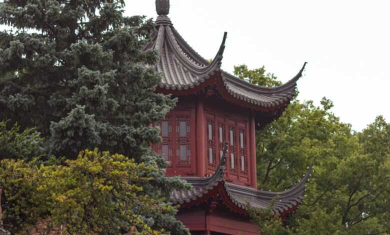 a tall red building sitting on top of a lush green forest