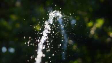 a close up of a water spout with trees in the background