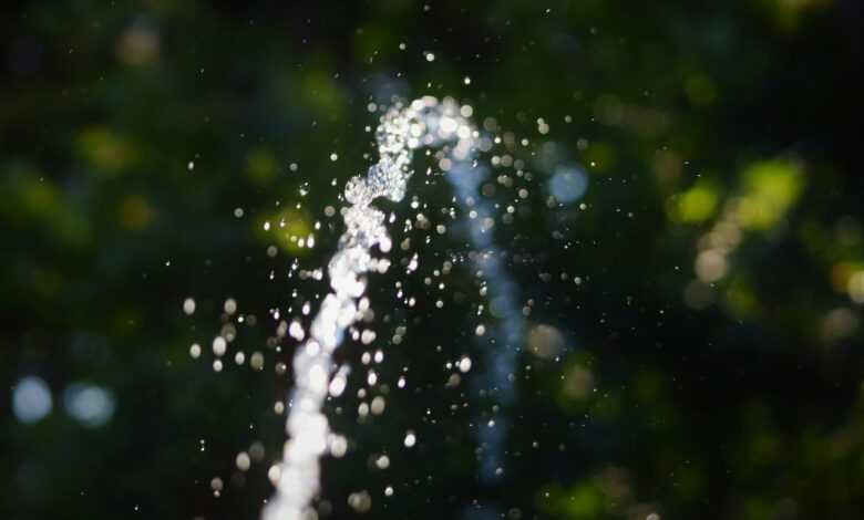 a close up of a water spout with trees in the background