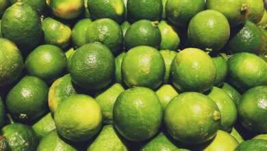 a pile of limes sitting on top of a pile of oranges