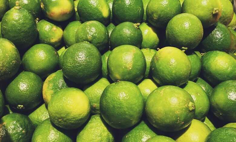 a pile of limes sitting on top of a pile of oranges