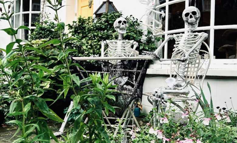 a skeleton sitting at a table in a garden